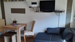 Ein modernes Wohnzimmer mit einer Couch, einem kleinen Tisch und einem an der Wand befestigten Fernseher.