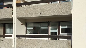 Ein mehrgeschossiges Gebäude mit einer Betonfassade, großen Fenstern und einem sichtbaren Balkon.