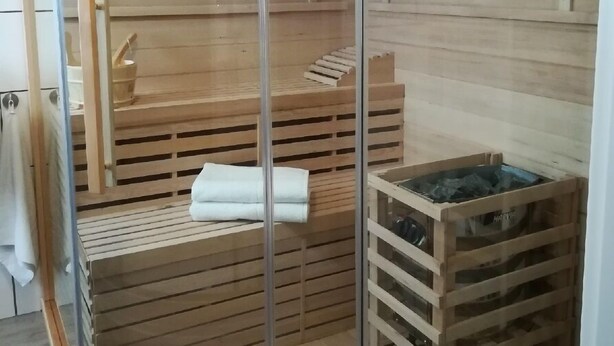 Un sauna avec des bancs en bois et une paroi en verre.