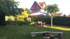 Un jardin avec une table de pique-nique, une construction en pierre et une maison en arrière-plan.