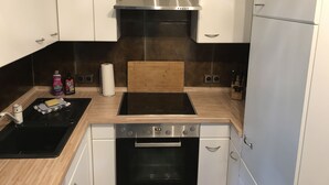 A modern kitchen with a built-in oven, a stovetop, and a stainless steel range hood.