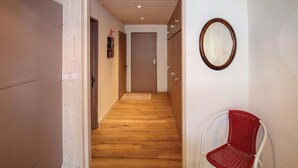 A hallway with wooden flooring, a red chair, and a mirror on the wall. - Nice apartment in Vals les Bains (Vals les Bains)