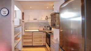 A compact kitchen with wooden cabinets, a stainless steel refrigerator, and a small island with a sink. - Nice apartment in Vals les Bains (Vals les Bains)