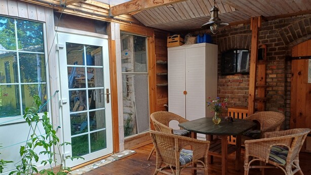 A wooden interior with a dining table and chairs, a white cabinet, and a brick wall. - Holiday apartment in a tiny village - pets welcome (Nordwestuckermark)