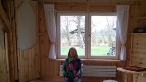 A wooden room with a large window, a person kneeling on a mat, and several bowls arranged on the floor. - Holiday apartment in a tiny village - pets welcome (Nordwestuckermark)