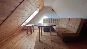 A loft-style room with a sloped ceiling, wooden floor, a sofa, a small table, and a window providing natural light. - Holiday apartment in a tiny village - pets welcome (Nordwestuckermark)