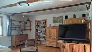 A cozy living room with wooden furniture, a television, and a bookshelf. - Holiday apartment in a tiny village - pets welcome (Nordwestuckermark)