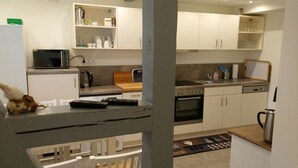 Une cuisine moderne avec des meubles blancs, un four à micro-ondes, une bouilloire et deux télécommandes posées sur le plan de travail.