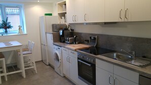 Une cuisine compacte équipée d’un lave-linge, d’un four et d’un évier.