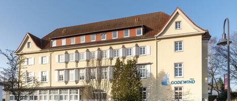 A multi-story hotel with a classic architectural style, featuring a prominent "GODEWIND" sign on the facade.