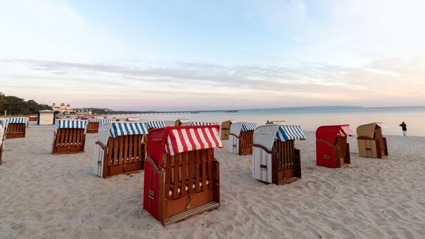 Beach chairs with striped awnings arranged on a sandy beach. - 3-room apartment Haus Godewind 10 in Binz, balcony, parking lot, beach chair on the beach (Binz)