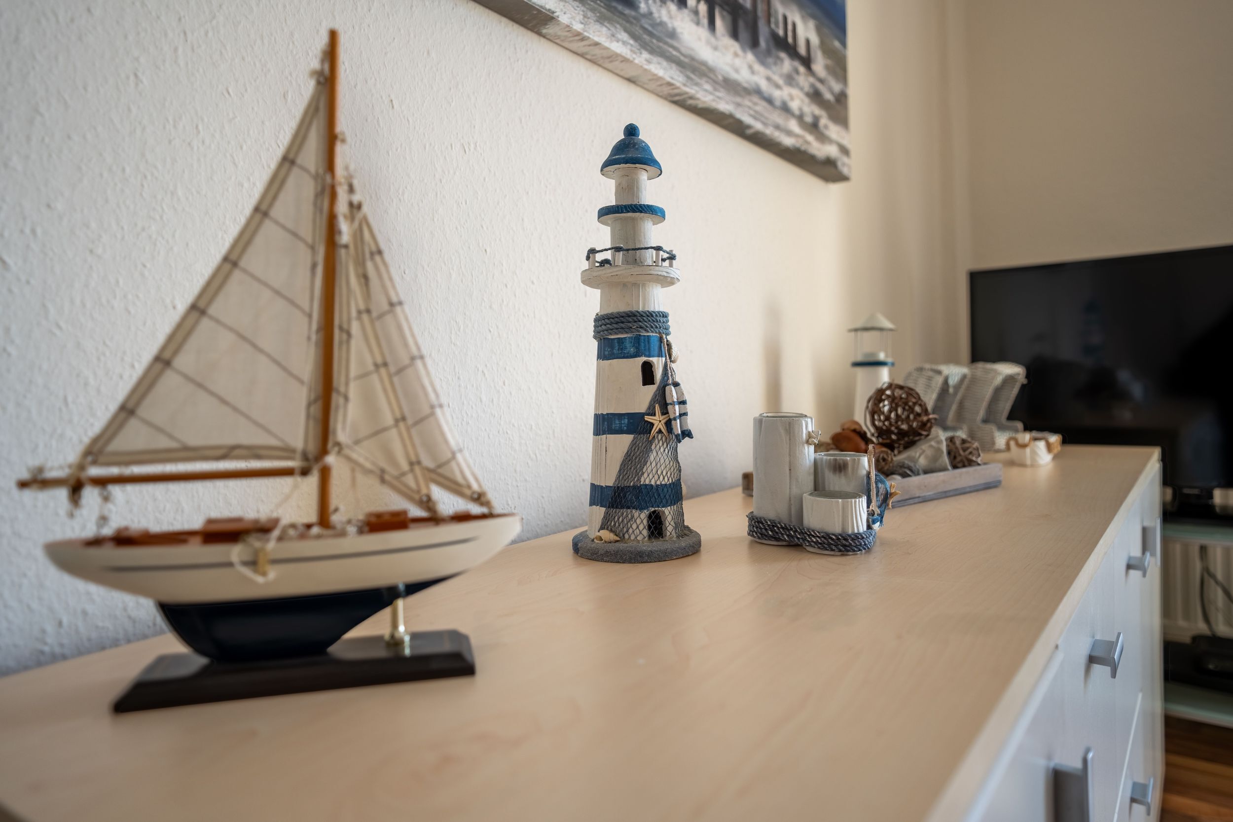 Un modèle de voilier et un phare sur une table en bois.
