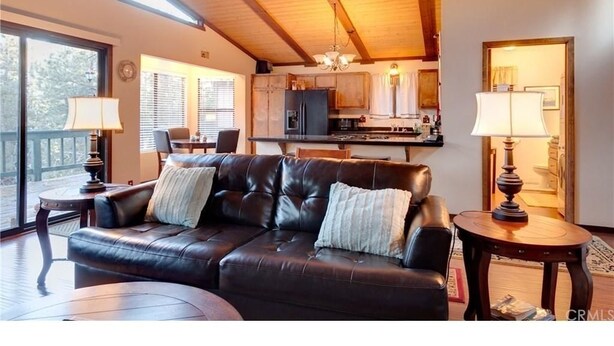 A cozy living room with a leather sofa, a dining table, and a kitchen in the background.