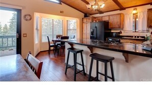 A kitchen with wooden beams, a large island with stools, and a view through the door.
