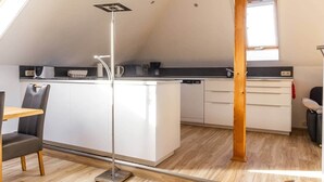 A compact kitchen with a central island, white cabinetry, and a modern pendant light.