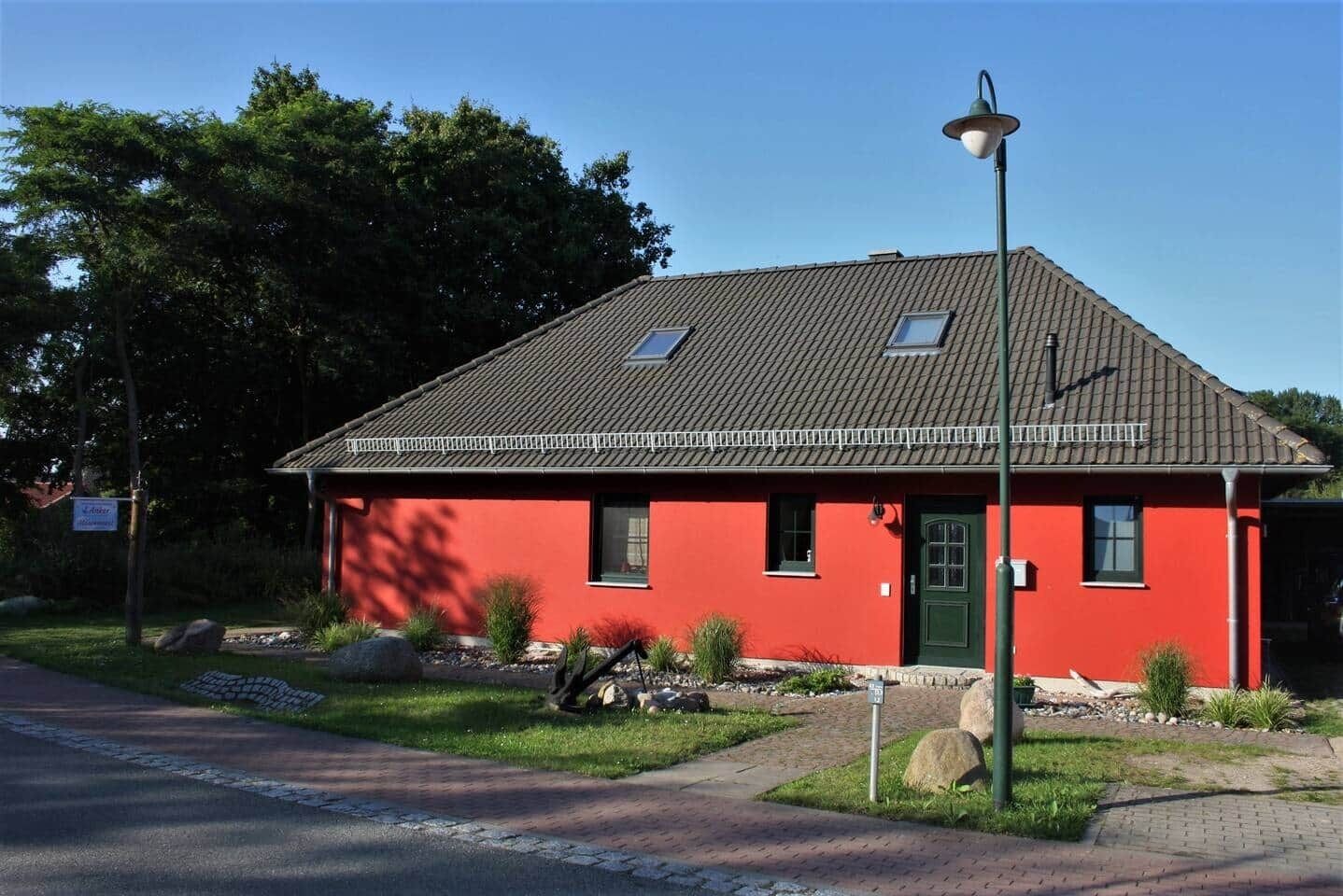 Un edificio rojo con techo inclinado, una puerta verde y una ventana pequeña.