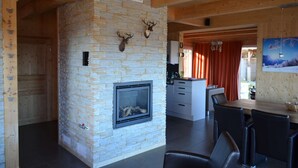 Un intérieur moderne agrémenté d’une cheminée en pierre, de poutres en bois et d’un coin repas.