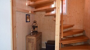 Un intérieur en bois comprenant un escalier, une armoire en bois et une petite table avec une lampe.