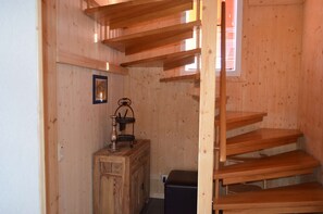 A wooden interior with a staircase, a wooden cabinet, and a small table with a lamp. - Luxury chalet in ski and hiking area with sauna + whirlpool (Klippitztörl, Bad St. Leonhard)