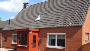 A red brick house with a grey tiled roof, a small window, and a number '20' on the door. - At the ice cream parlor, Germany (Pahlen)