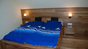 Ein Bett mit Holz-Kopfstütze, zwei Nachttische und eine blaue Bettdecke.