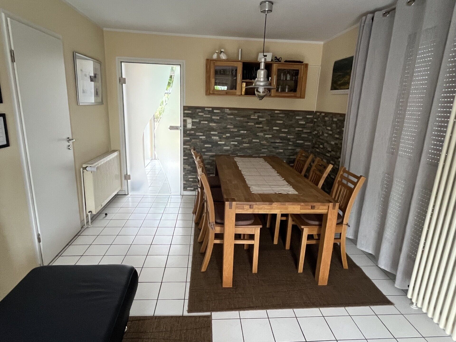 Un espace repas avec une table et des chaises en bois, une cuisine équipée d’armoires et une vue sur l’extérieur.
