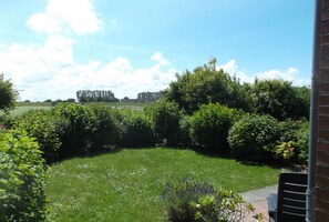 Un jardin avec une pelouse, des arbustes et un mur en briques.