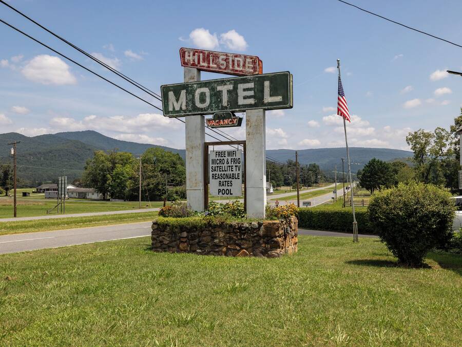 A motel sign with a 'VACANCY' indicator, an American flag, and a sign offering free WiFi, micro & fridge, and satellite TV at reasonable rates.