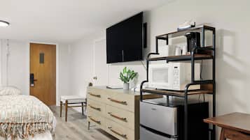 Un dormitorio moderno con cama, cómoda, televisor, microondas y cafetera.
