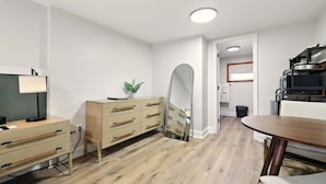 A modern room with a wooden dresser, a mirror, a desk with a lamp, and a dining table. - Hillside (Luray)