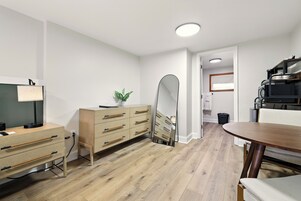 Una habitación moderna con un aparador de madera, un espejo, un escritorio con una lámpara y una mesa de comedor.