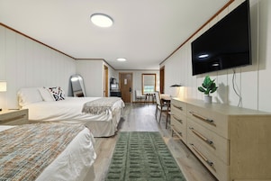 Una habitación de hotel con dos camas, televisión, escritorio y cómoda.