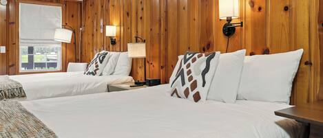 Habitación de hotel con dos camas, paneles de madera y dos lámparas fijadas a la pared.