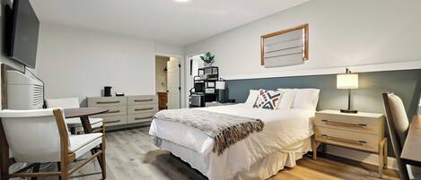 Un dormitorio moderno con cama, mesitas de noche, escritorio y televisor.