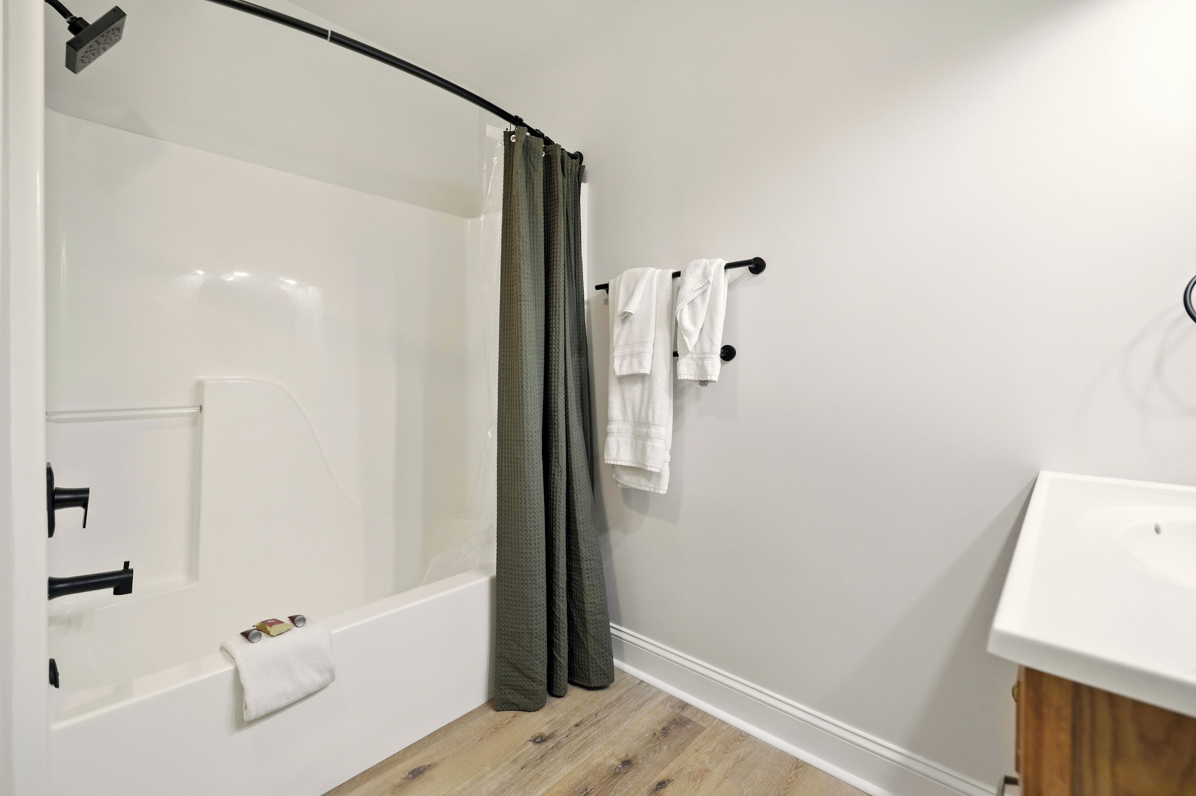 A modern bathroom with a glass shower enclosure, a white sink, and a wooden cabinet.