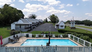 A motel with a swimming pool, outdoor seating, and a road in the background. - Hillside (Luray)