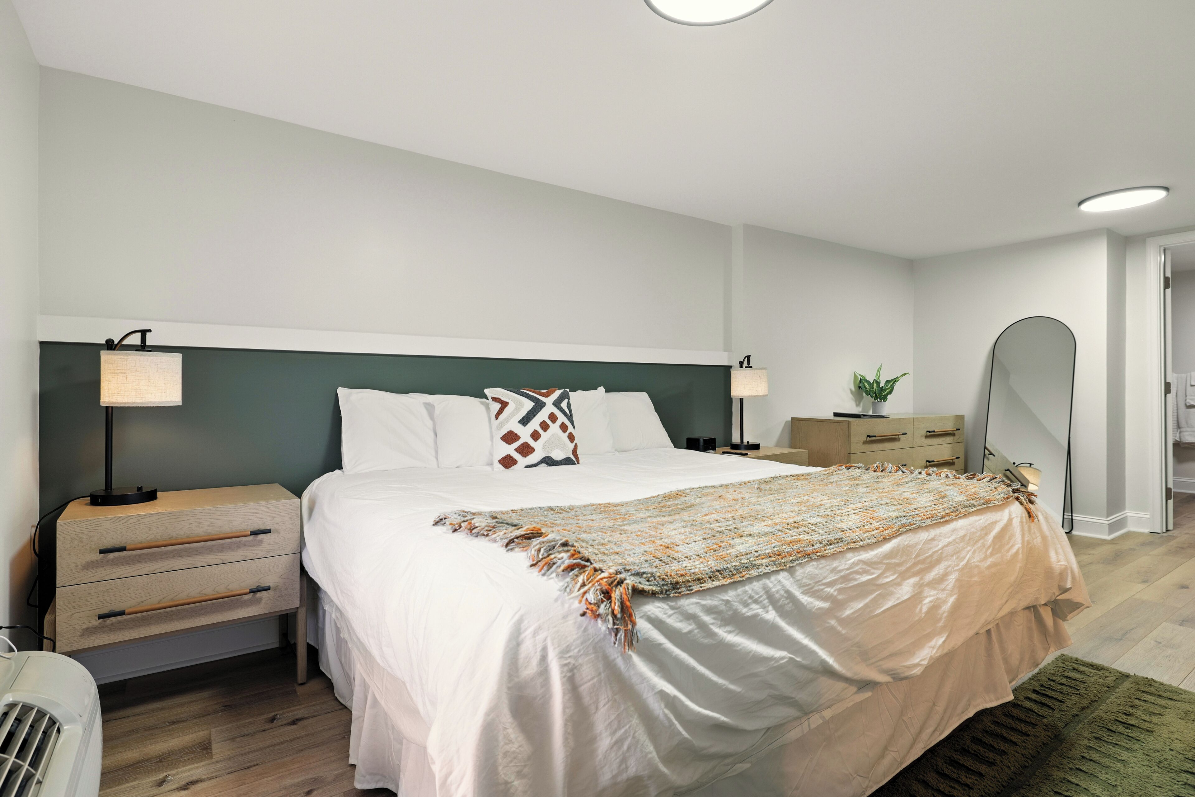 Une chambre à coucher moderne avec un grand lit, des tables de chevet et un miroir.