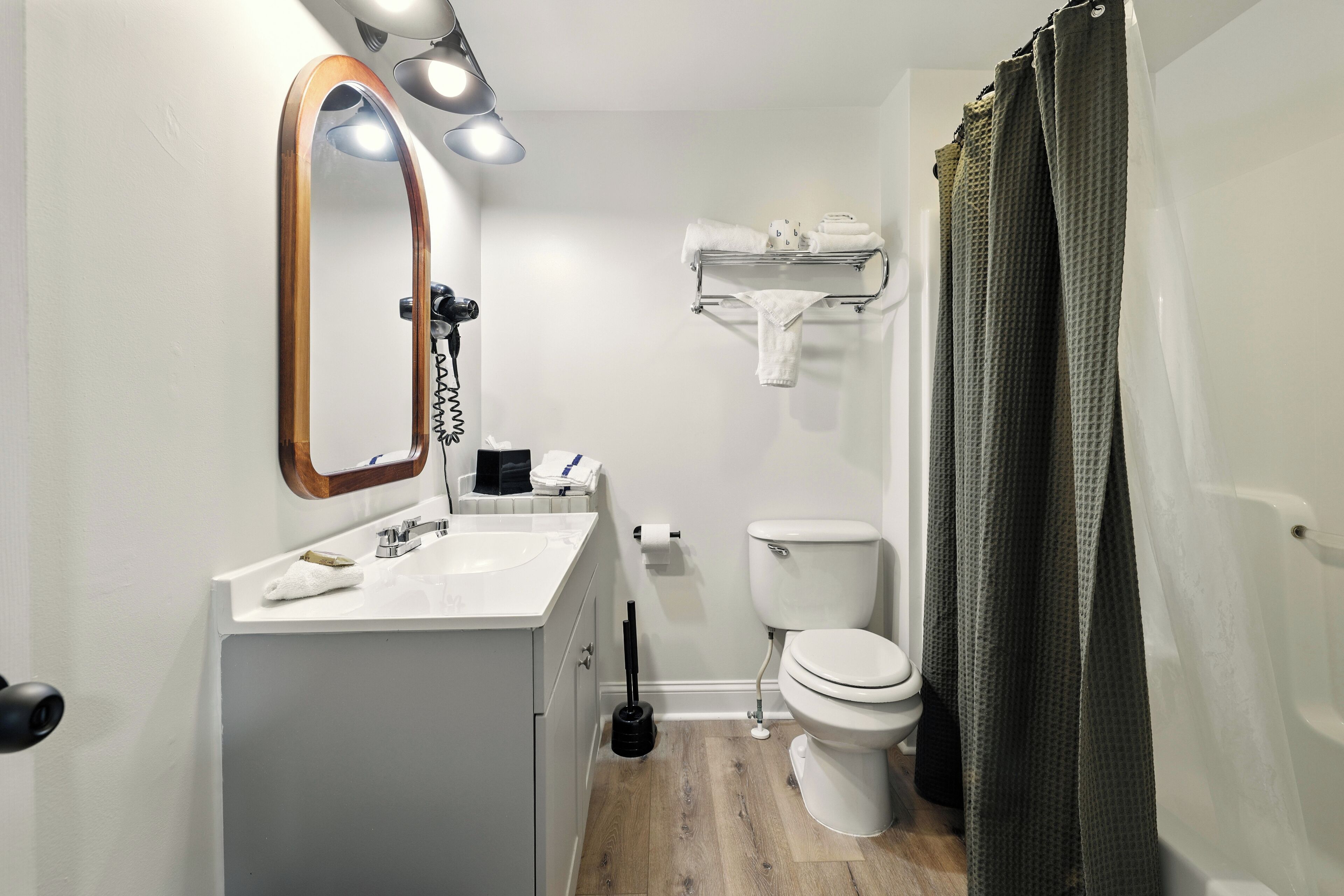 A bathroom with a white sink, a mirror, a toilet, and a shower curtain.