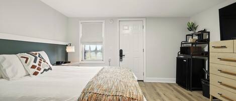 Un dormitorio con cama, mesita de noche, lámpara y armario.