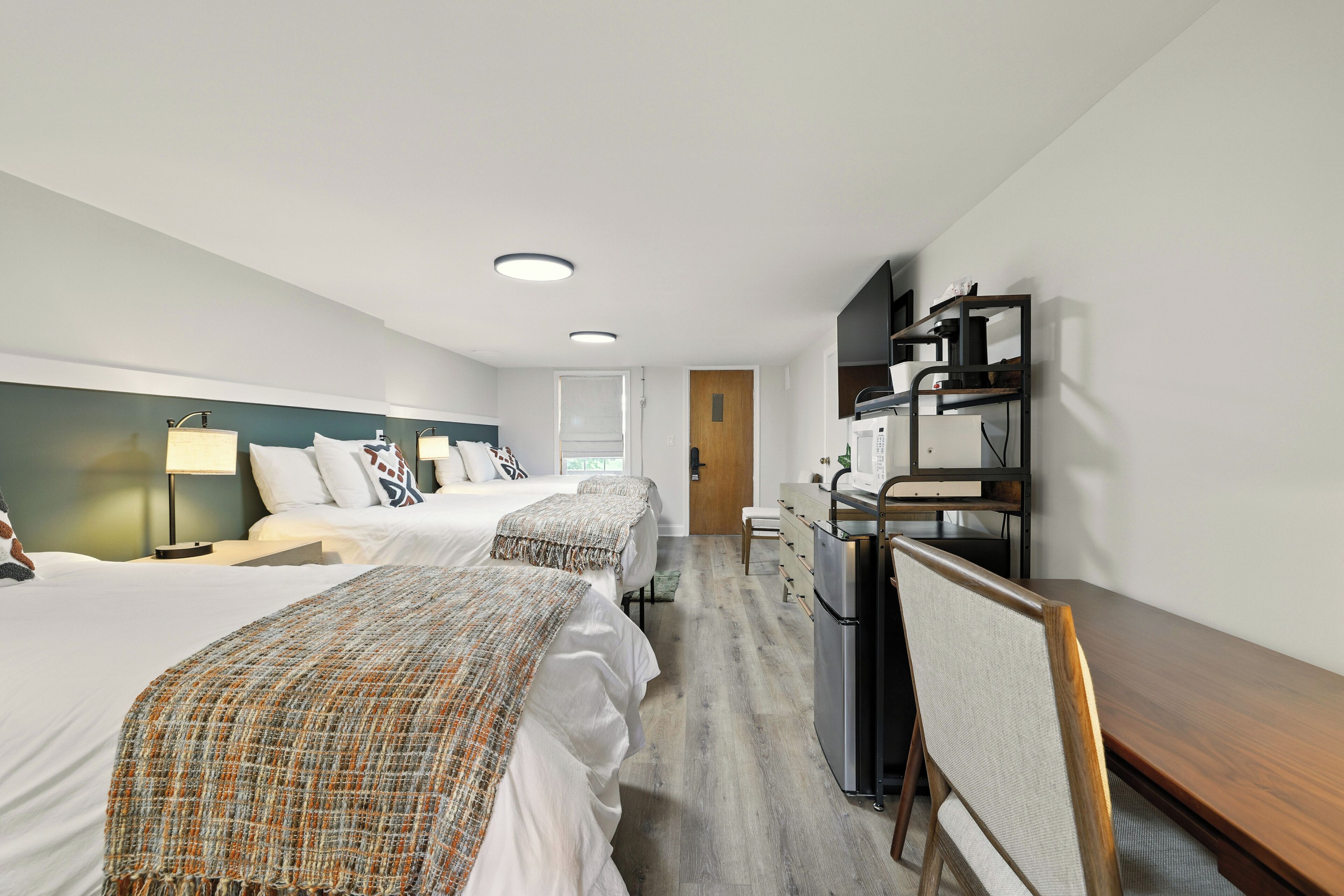 Een hotelkamer met twee bedden, een bureau, een kast en een magnetron.