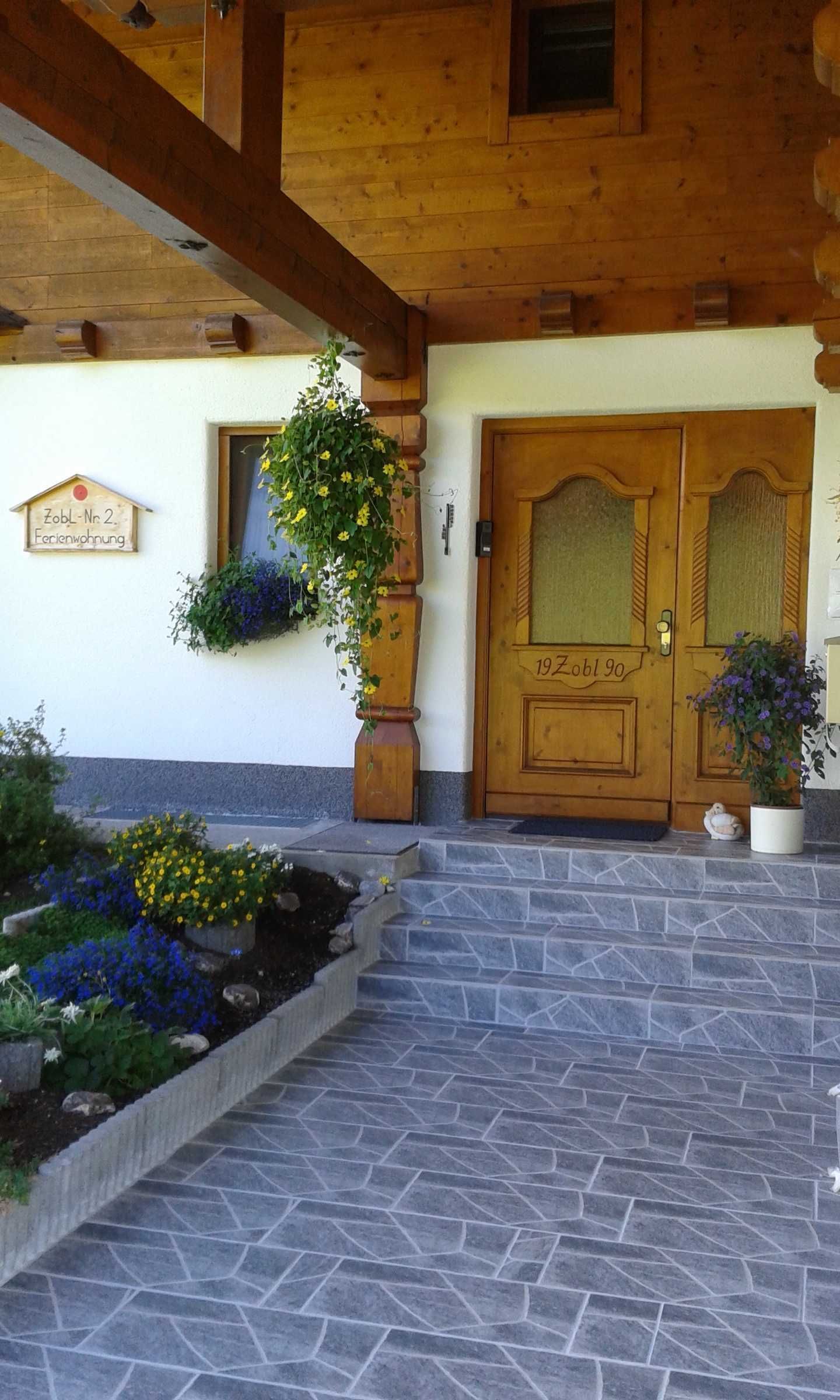 Un edificio de madera con una escalera de piedra que conduce a una puerta con la inscripción '19 Zobl 90'.