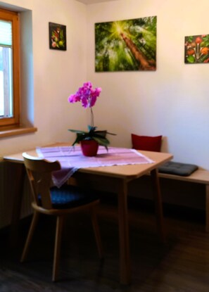 Una zona de menjador amb una taula, cadires, una orquídia en test i una panxa de vidre.