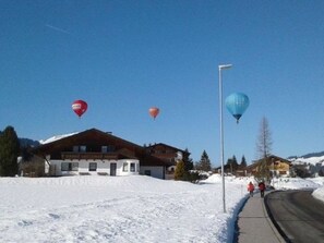 Un edifici amb teulada inclinada, terra coberta de neu i cel serè.