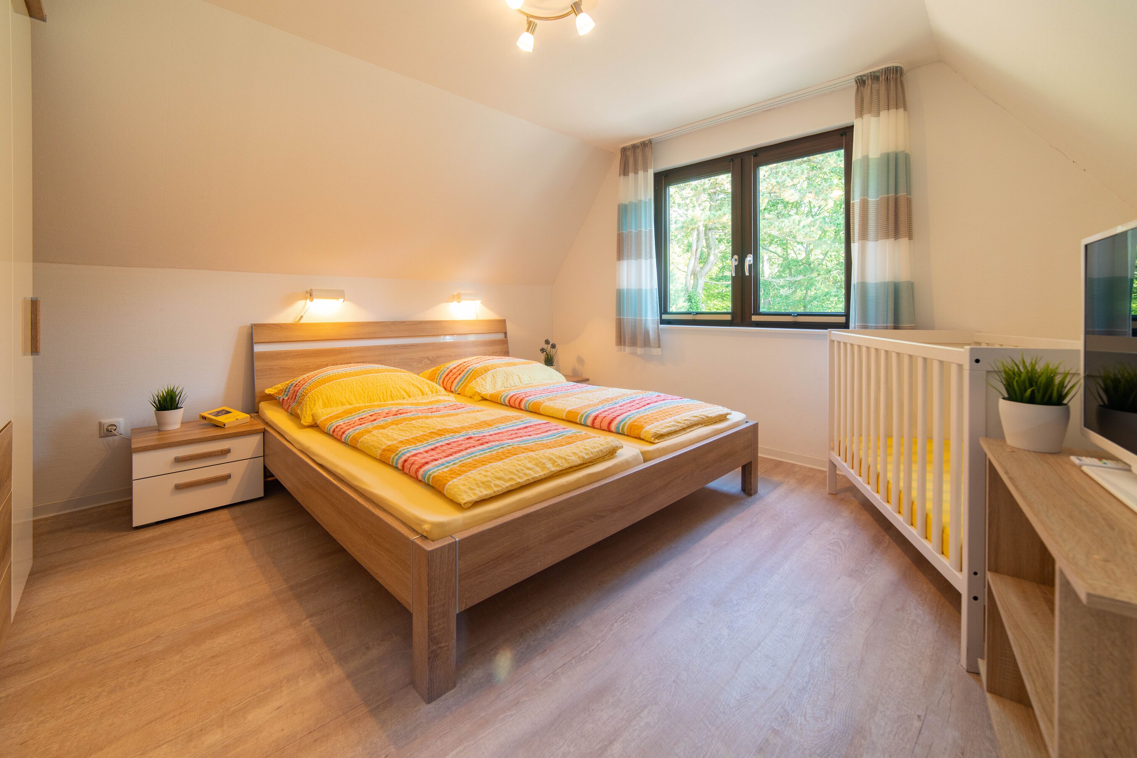 Une chambre à coucher avec un lit en bois, des tables de chevet, un radiateur et une fenêtre avec des rideaux.