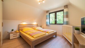 Une chambre à coucher avec un lit en bois, des tables de chevet, un radiateur et une fenêtre avec des rideaux.