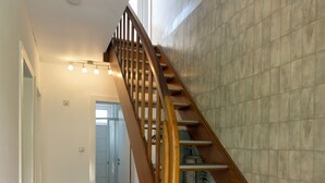 Un escalier en bois, doté d’une rampe, mène à un palier.