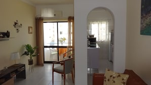Un soggiorno con un divano, un tavolo da pranzo e sedie. Si intravede una cucina attraverso un arco.