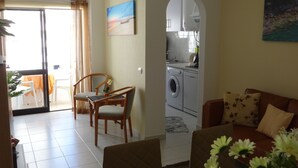 Un soggiorno con divano, tavolo da pranzo e sedie. Si intravede una cucina attraverso un arco.