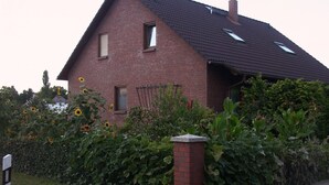 A brick house with a sloped roof, two windows, and a chimney.