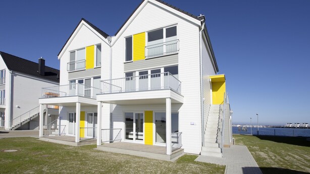 A modern two-story building with balconies, a staircase, and a view of the sea. - Ostseeliebe - Ground Floor, waterfront, Terrace, Whirlpool Bath, Infrared Sauna (Olpenitz)